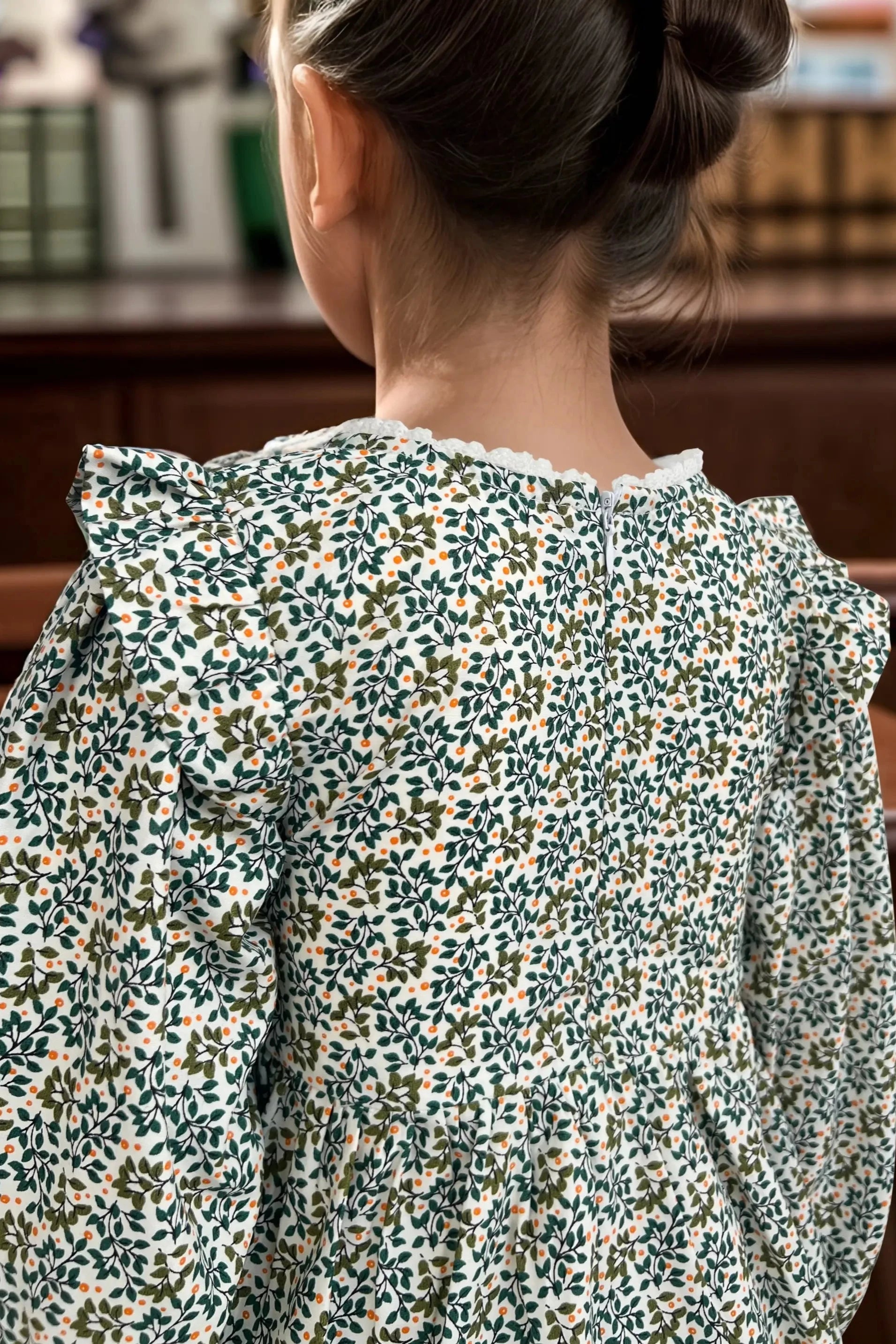 Back close up view of a green dress for baby girl, designed for kids aged 2 to 9 years old.