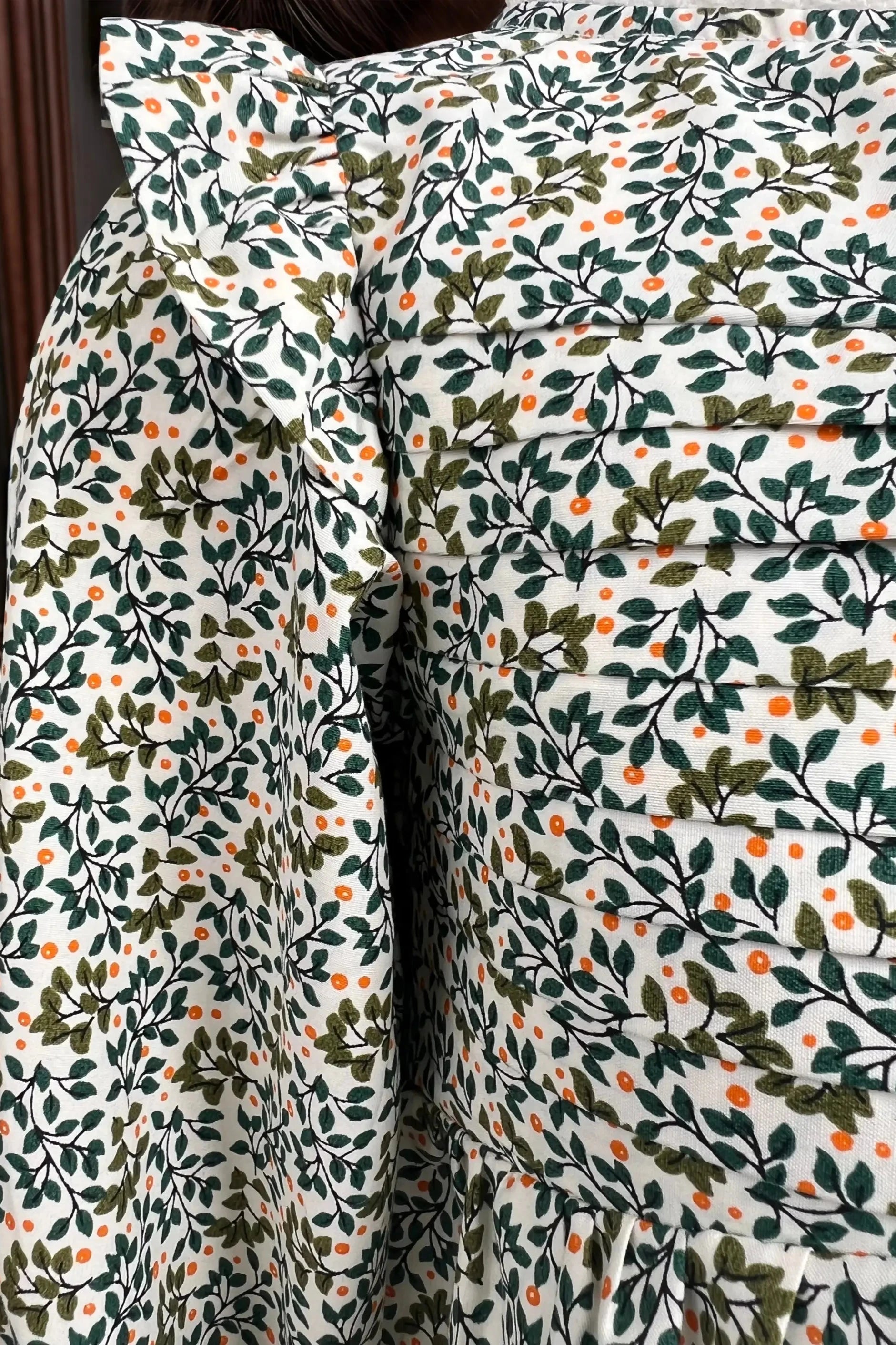 Close up front view of hand of a green dress for baby girl, designed for kids aged 2 to 9 years old.