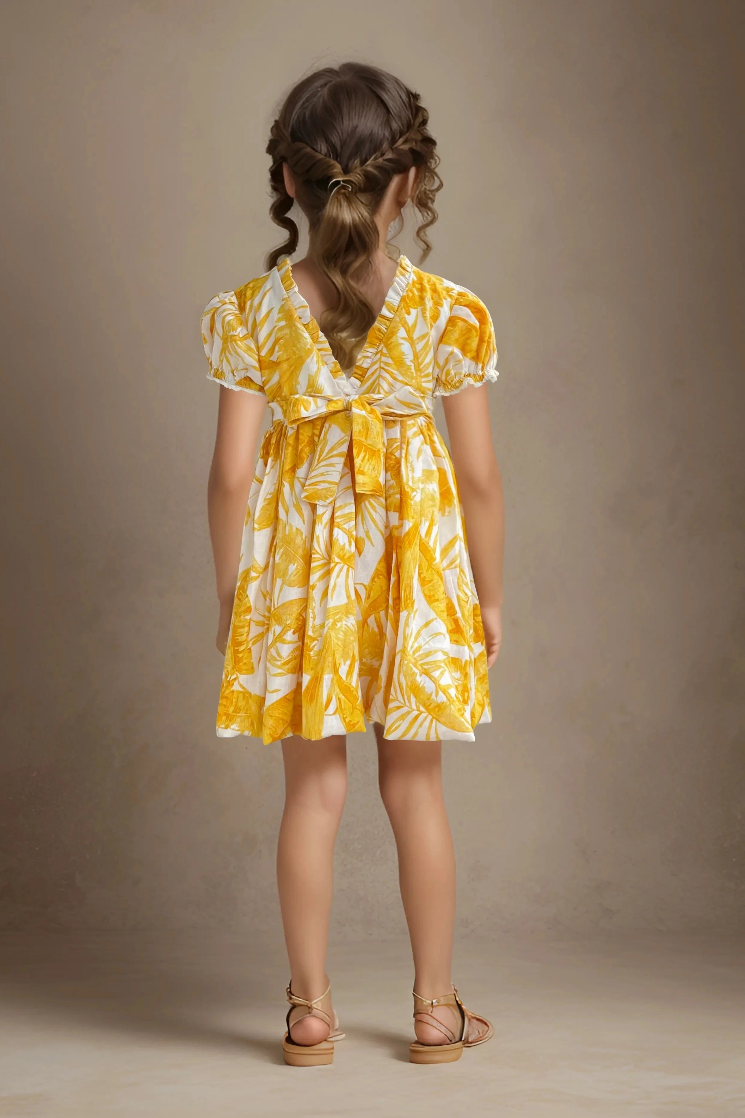 Full back view of a yellow floral printed balloon dress for girls, made of cotton.